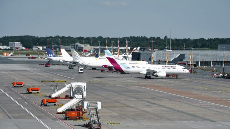 A busy scene at Hamburg Airport with various planes parked at the terminal during the day.
